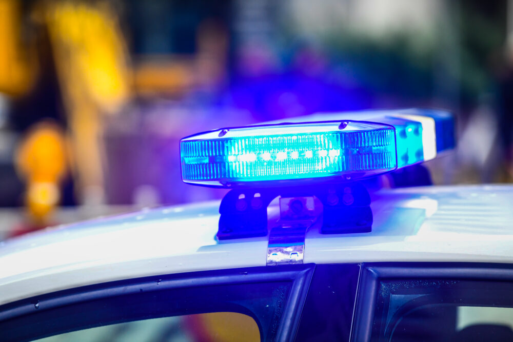 Blue police lights illuminated on top of a patrol car, the blurred city background emphasizing the focus on the lights during a 341 meeting.