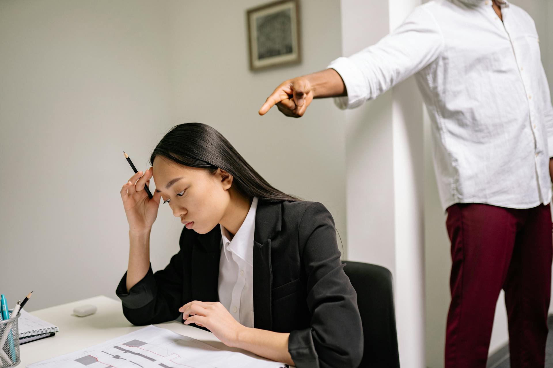 woman being pointed at at work desk